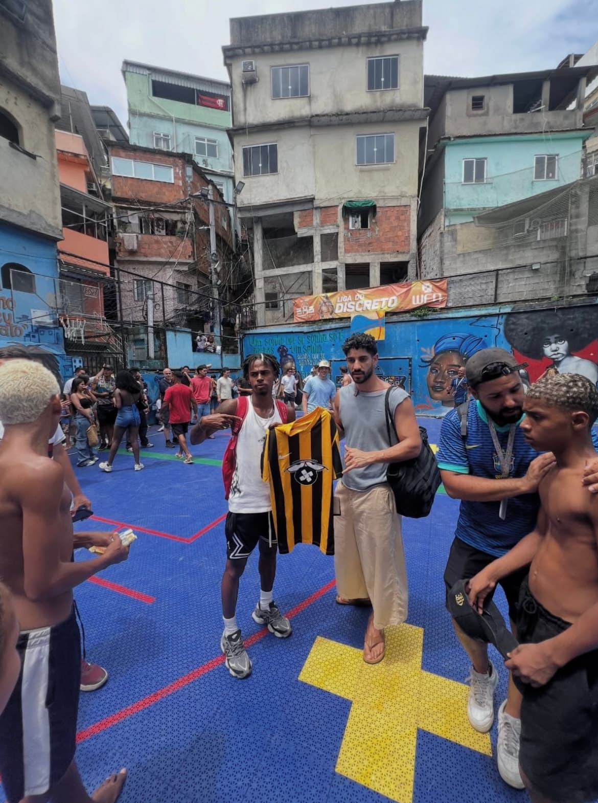 Ryan holding a football jersey in Rocinha with a traveller.
